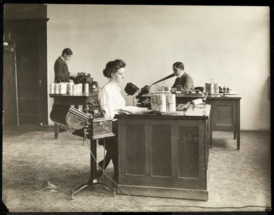 Interior view of a woman typing from a dictating machine and a man dictating into another at the Edison Phonograph Co., West Orange, New Jersey by Byron Company